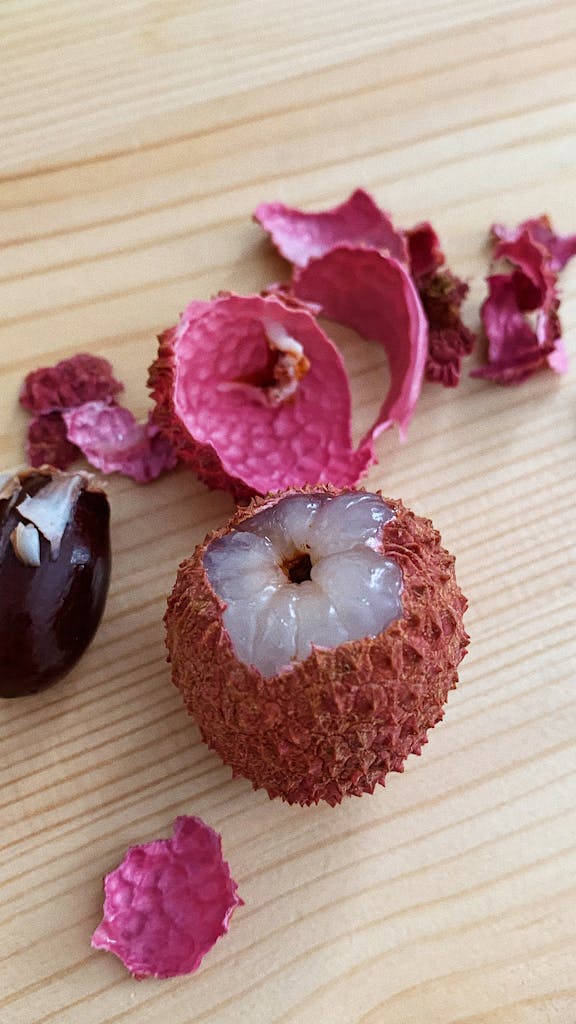Close-up shot of lychee fruit with peel and seed on a wooden surface, showcasing freshness.